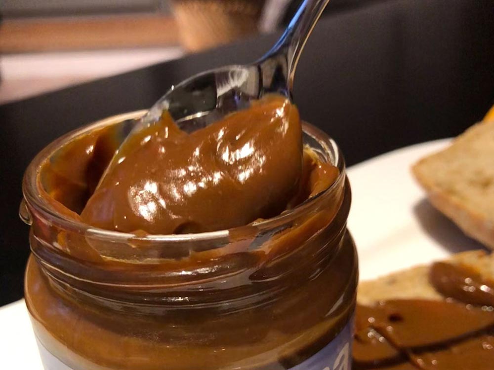 Ein Löffel holt Dulce de Leche aus einem Glas